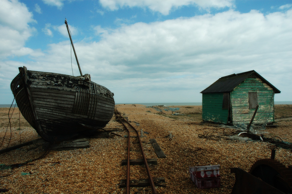 Digital photograph of abandoned boat, Dungeness, Kent railway line hut beach pebbles sea sky seaside net