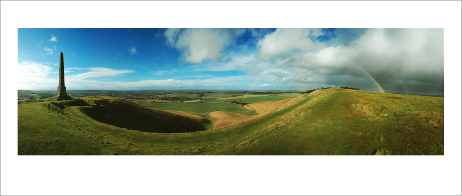 Digital landscape panoramic photograph of Cherhill Downs Monument with rainbow, Wiltshire
